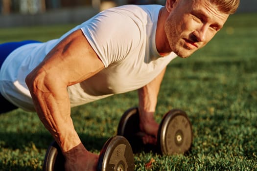 athletic man training with dumbbells in the morning Park. High quality photo