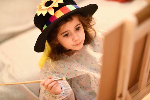 Happy little girl painting a picture at home