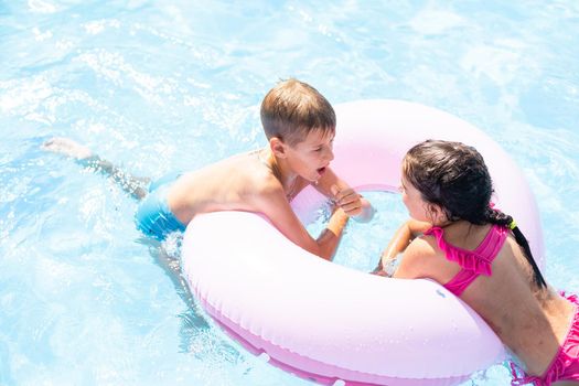 Kids having fun playing in swimming pool on summer vacation.