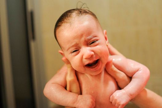 Baby girl two months old having her bath and crying