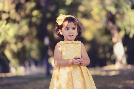 Portrait of a little girl running and playing in the park wearing a beautiful dress