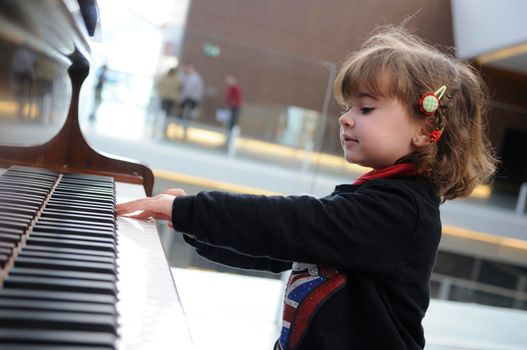 Adorable little girl having fun playing the piano