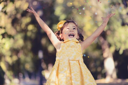 Portrait of a little girl running and playing in the park wearing a beautiful dress