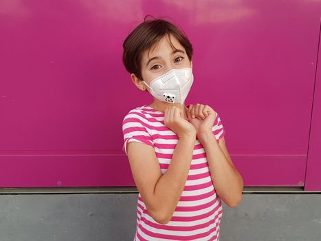 Happy Child girl wearing a protection mask against coronavirus during Covid-19 pandemic. KN95 mask.