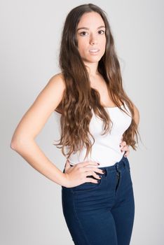 Portrait of young woman with long hair wearing white t-shirt and blue jeans on white background