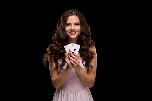 Attractive young woman in a sexy light dress holding the winning combination of poker cards. Two Aces. Studio shot on a black background. Casino