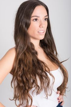 Portrait of young woman with long hair wearing white t-shirt and blue jeans on white background
