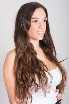 Portrait of young woman with long hair wearing white t-shirt and blue jeans on white background