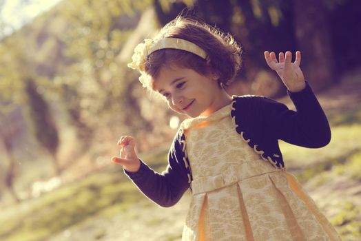 Portrait of a little girl running and playing in the park wearing a beautiful dress