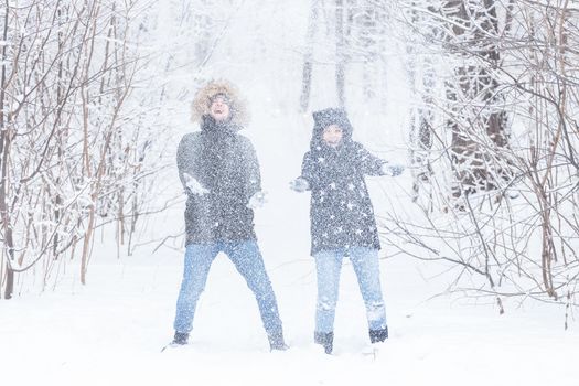 man and woman having fun and playing with snow in winter forest