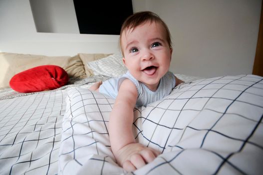 Smiling baby girl lying on her parents bed with funny expression