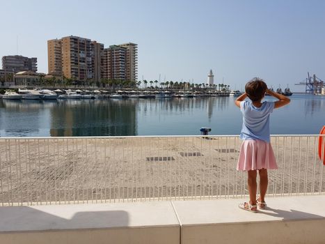 Little girl looking at the Port of Malaga in Andalusia, Spain.