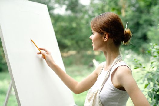 an artist in nature draws on an easel with a pencil. High quality photo