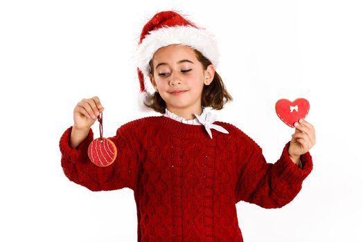 Adorable little girl wearing santa hat with Christmas biscuits isolated on white background. Winter clothes