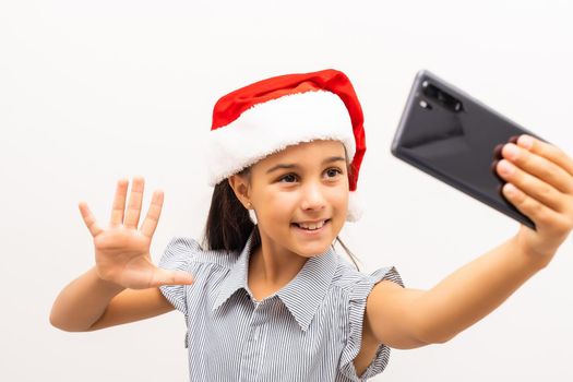 Cute little girl in Santa hat and with mobile phone on white background.