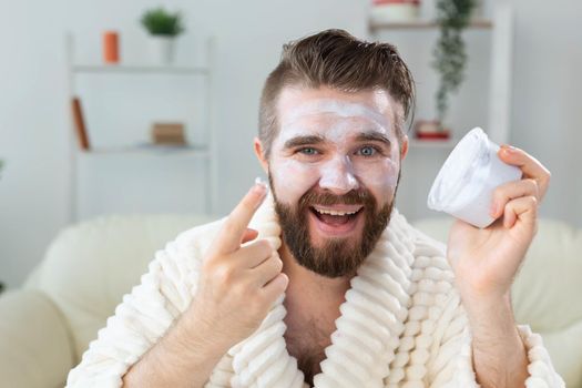 Bearded guy applying anti-wrinkle cream on his face. Skin care and spa for man concept