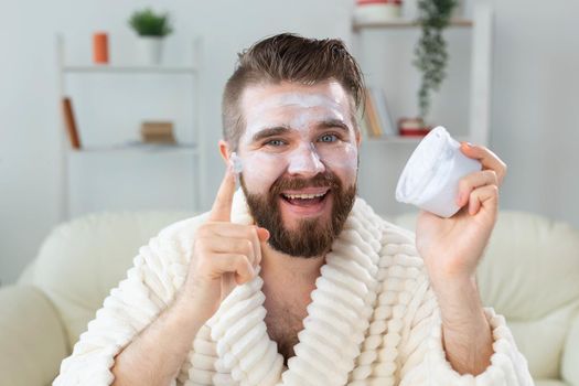 Closeup of handsome young man applying facial cream in front of mirror