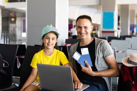 Handsome young father and little daughter using laptop at airport.