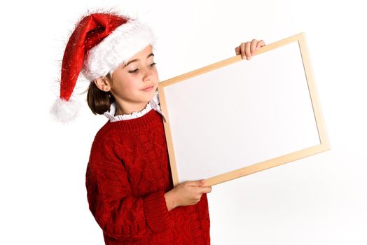 Little girl wearing santa hat holding blank board for advertisementon on white background. Invitation to christmas activities. Winter clothes