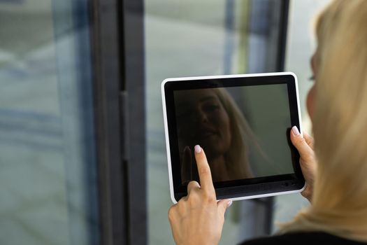 Portrait of a successful woman using digital tablet during quick break in front a corporate building