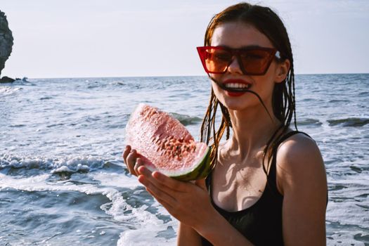 pretty woman in a black swimsuit with a watermelon in her hands summer Ocean. High quality photo
