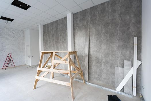 Repair in the apartment. building painter's goat in the interior of a bright room with fresh plastered walls. White walls in a building construction house