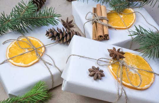 New Year's composition. On beige craft paper, gift boxes, dry orange slices, pine cones, cinnamon, cloves, spruce branches. Cozy Christmas concept