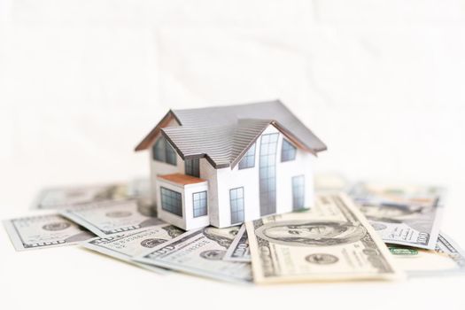 mortgage, investment, real estate and property concept - close up of home model, dollar money.