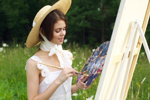 Woman in white dress outdoors artist drawing easel. High quality photo