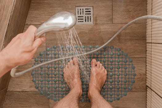 Men's feet stand on an anti-slip plastic mat on the bathroom floor. Care and men's body hygiene.