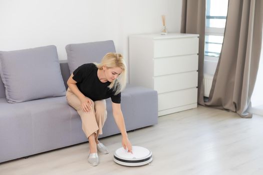 Modern life concept, woman relaxing, automatic robotic hoover clean the room while.