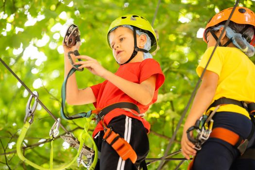 Happy child climbing in the trees. Rope park. Climber child. Early childhood development. Roping park. Balance beam and rope bridges. Rope park - climbing center.