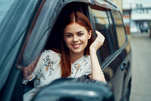 cheerful woman driving a car looks out of the window. High quality photo