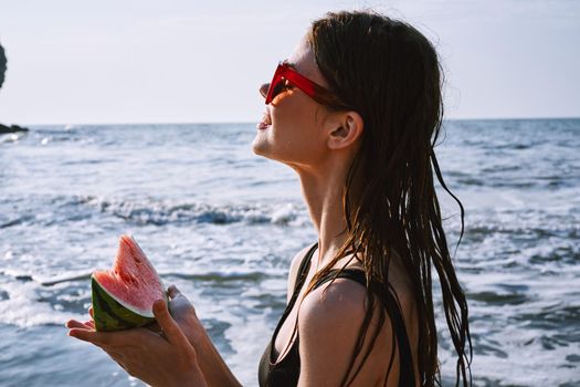 pretty woman in a black swimsuit with a watermelon in her hands summer Ocean. High quality photo