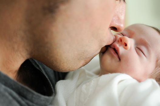 Father kissing his newborn baby girl. Close-up portrait
