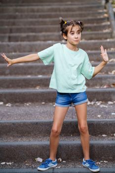 Nine-year-old girl dancing on the steps of a city park.
