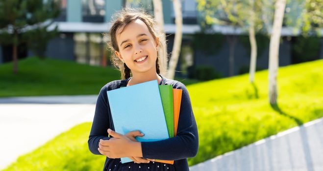 Little beautiful smiling girl holding book, going to school. close up portrait, childhood. kid hugging a book. lifestyle, interest, hobby, free time, spare time.