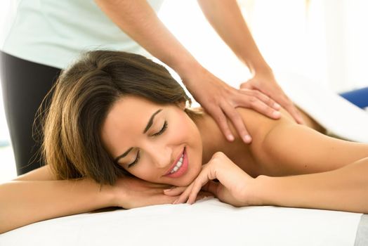 Young woman receiving a back massage in a spa center. Female patient is receiving treatment by professional therapist.