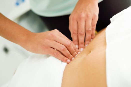 Hands massaging female abdomen.Therapist applying pressure on belly. Woman receiving massage at spa salon