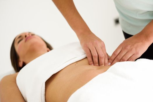 Hands massaging female abdomen.Therapist applying pressure on belly. Woman receiving massage at spa salon
