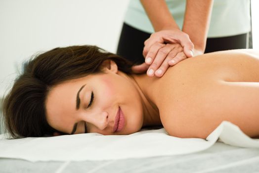 Young woman receiving a back massage in a spa center. Female patient is receiving treatment by professional therapist.