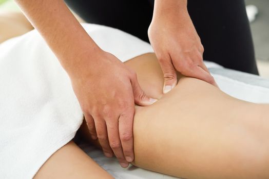 Medical massage at the leg in a physiotherapy center. Female physiotherapist inspecting her patient.