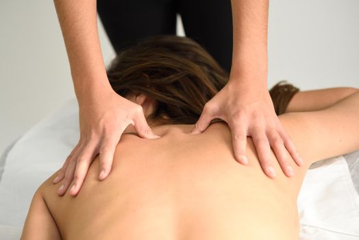 Young woman receiving a back massage in a spa center. Female patient is receiving treatment by professional therapist.