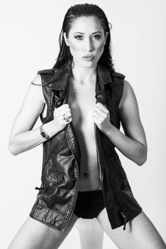 Brunette woman with blue eyes wearing black leather jacket and panties on white background. Studio shoot