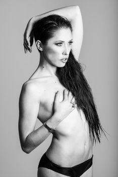 Half naked brunette woman wearing panties with very long curly hair on white background. Studio shot