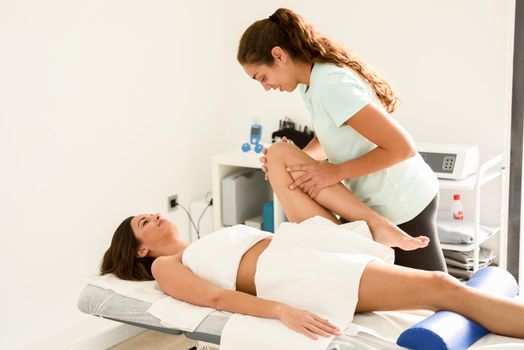 Medical massage at the leg in a physiotherapy center. Female physiotherapist inspecting her patient.