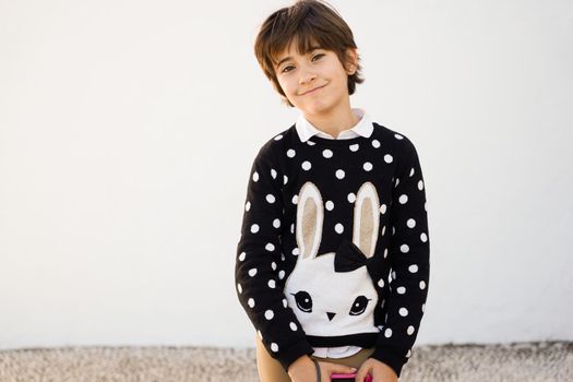 Nice seven years old girl with short hair smiling on camera on a white wall.