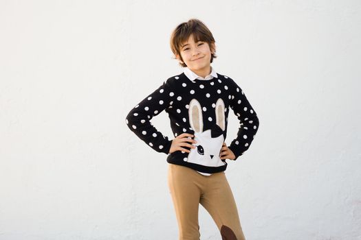 Nice seven years old girl with short hair smiling on camera on a white wall.