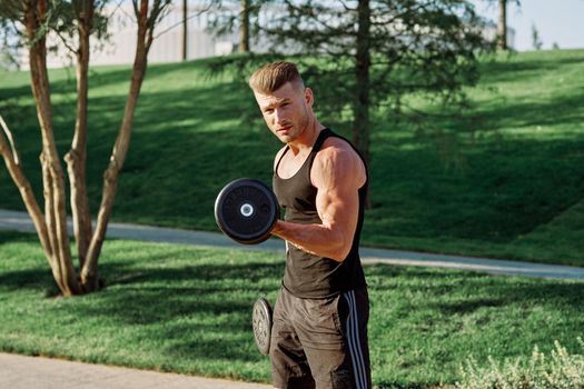 pumped up sports Vykhino in the park with dumbbell workout. High quality photo