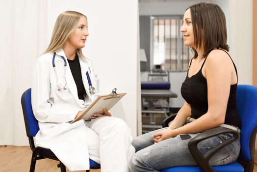 Female doctor explaining diagnosis to her patient. Brunette woman having consultation with blonde girl in medical office.